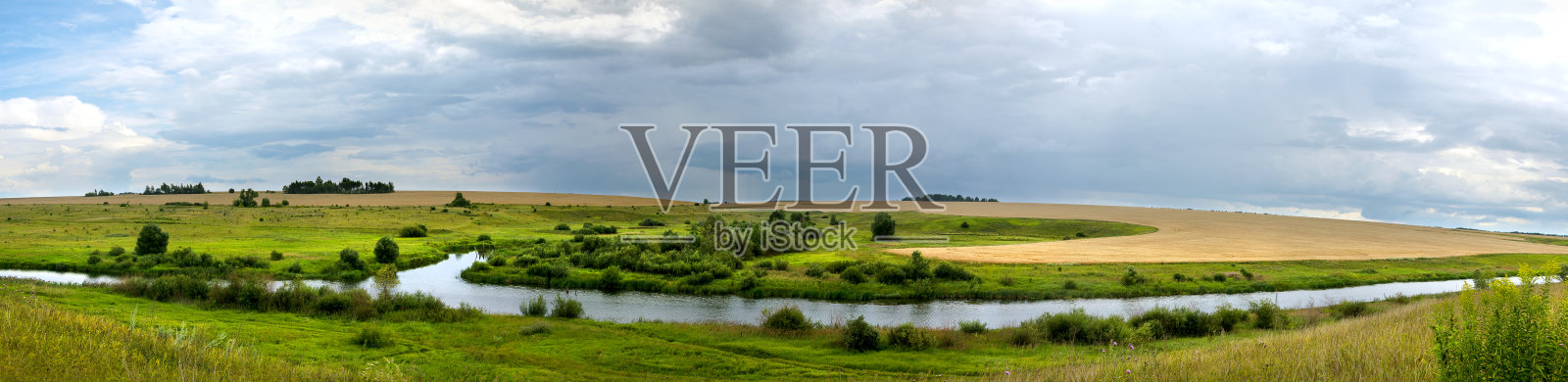 夏日全景，乌云密布，平静的河流和绿色的草地。照片摄影图片