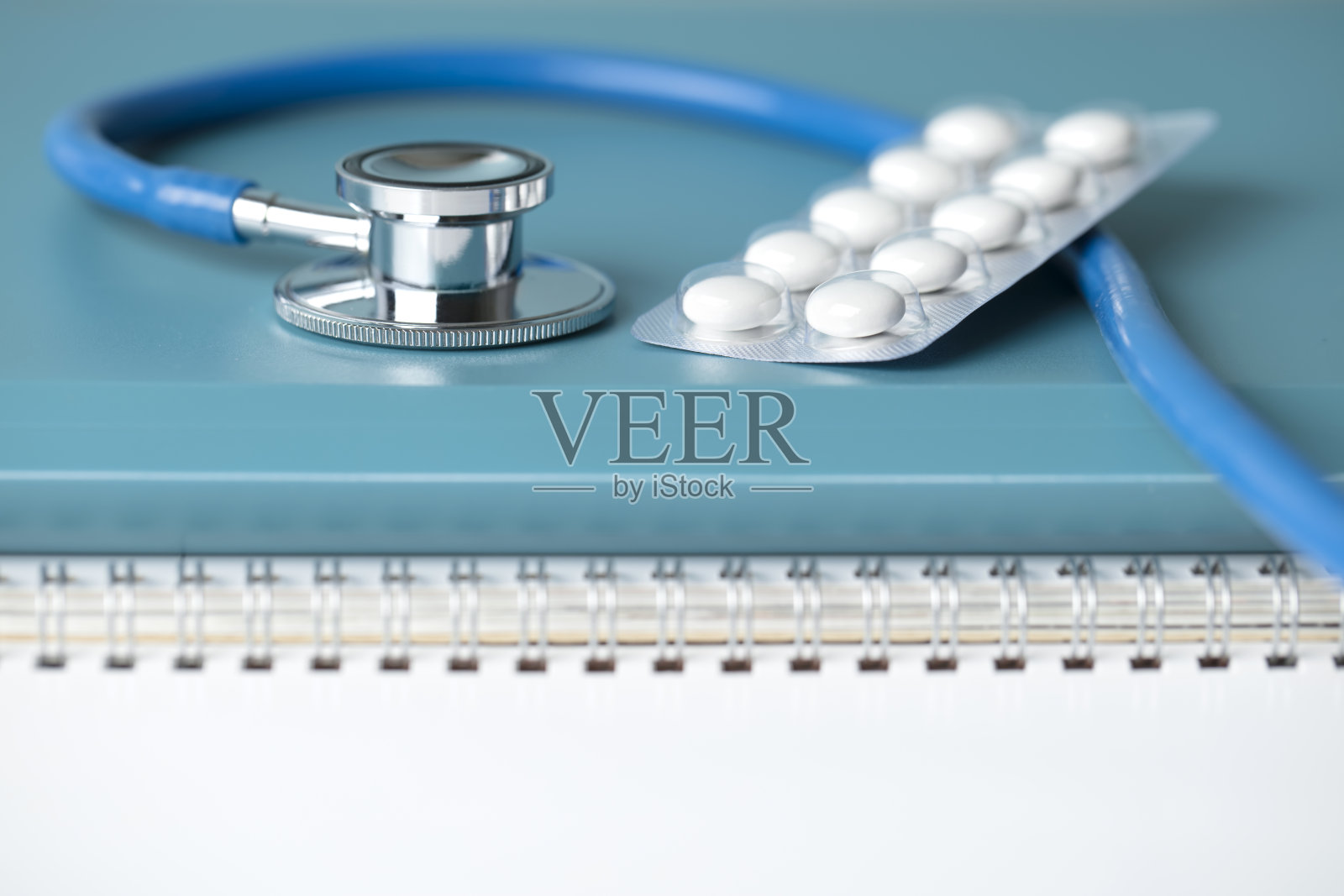 医学概念-听诊器与一些药丸水泡在螺旋笔记本上照片摄影图片