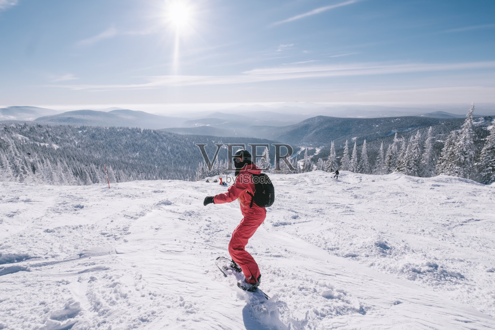 女人在阳光明媚的雪坡上骑滑雪板，美丽的山谷景色。运动户外生活方式照片摄影图片