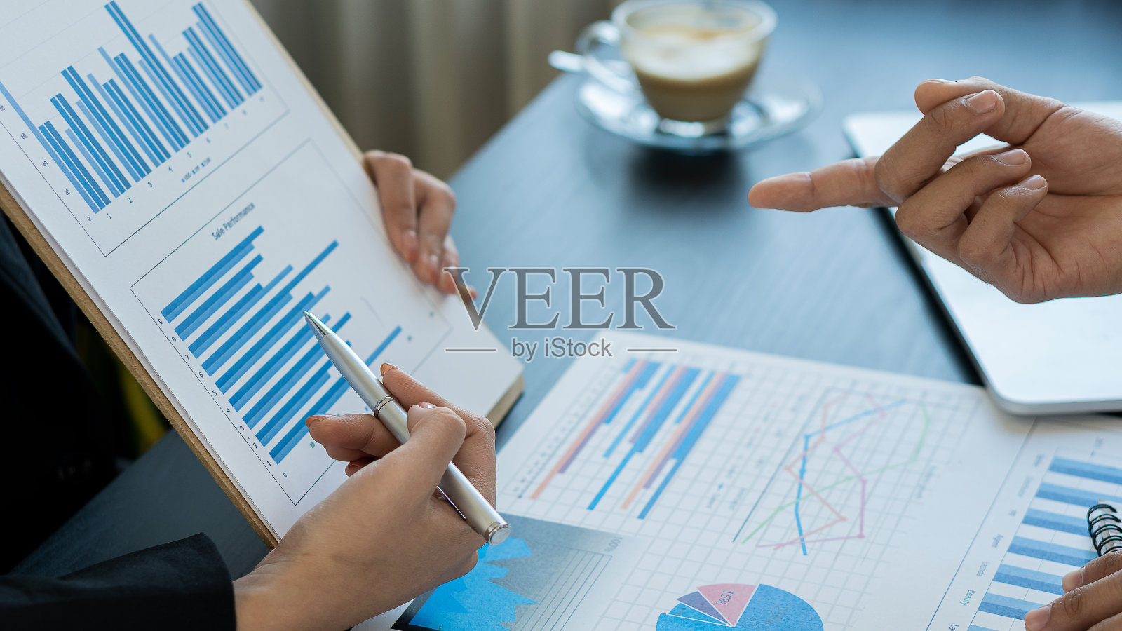 在讨论财务和市场文件、会议、数据分析、财务图表和办公室图表时，讨论业务策略的业务人员会使用笔记本电脑和计算器进行协作。照片摄影图片