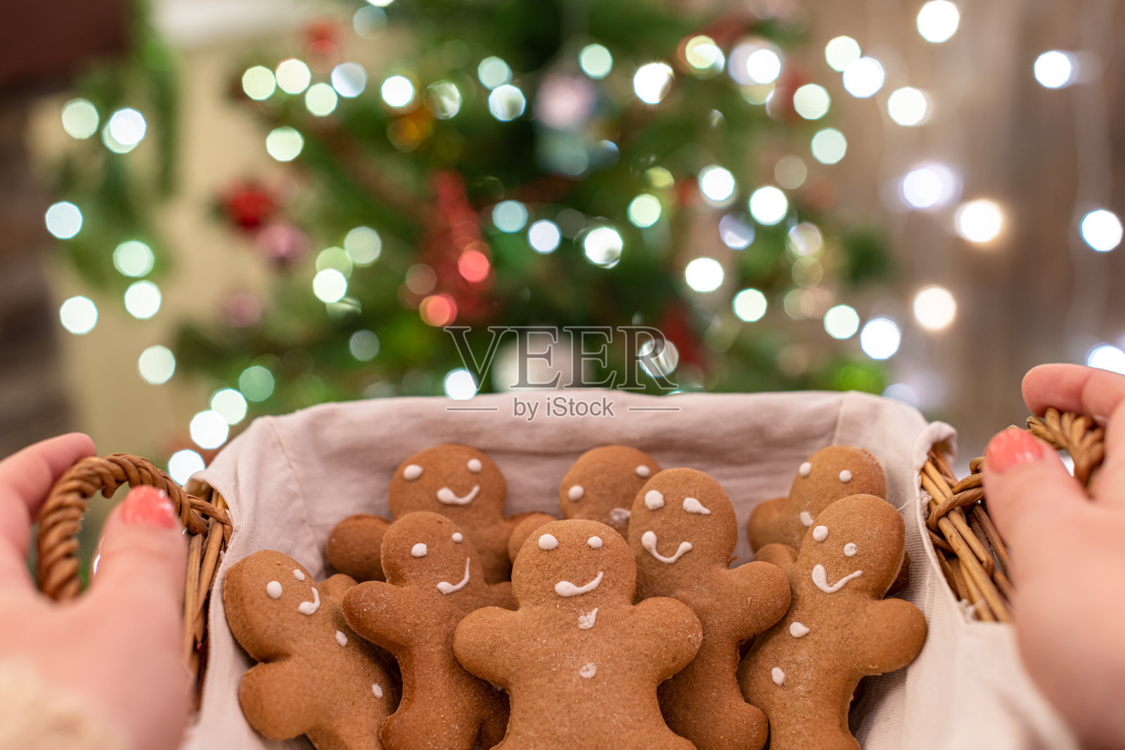 女人手里拿着草篮和姜饼男人在圣诞树的背景与美丽的光散。副本的空间。照片摄影图片