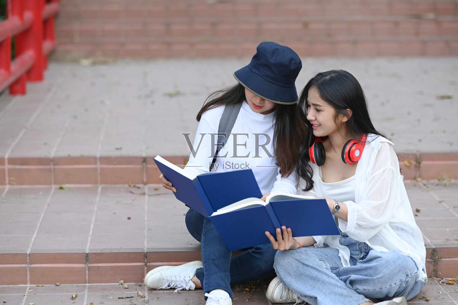 快乐的大学生拿着书，在校园里一起谈论功课比较。照片摄影图片