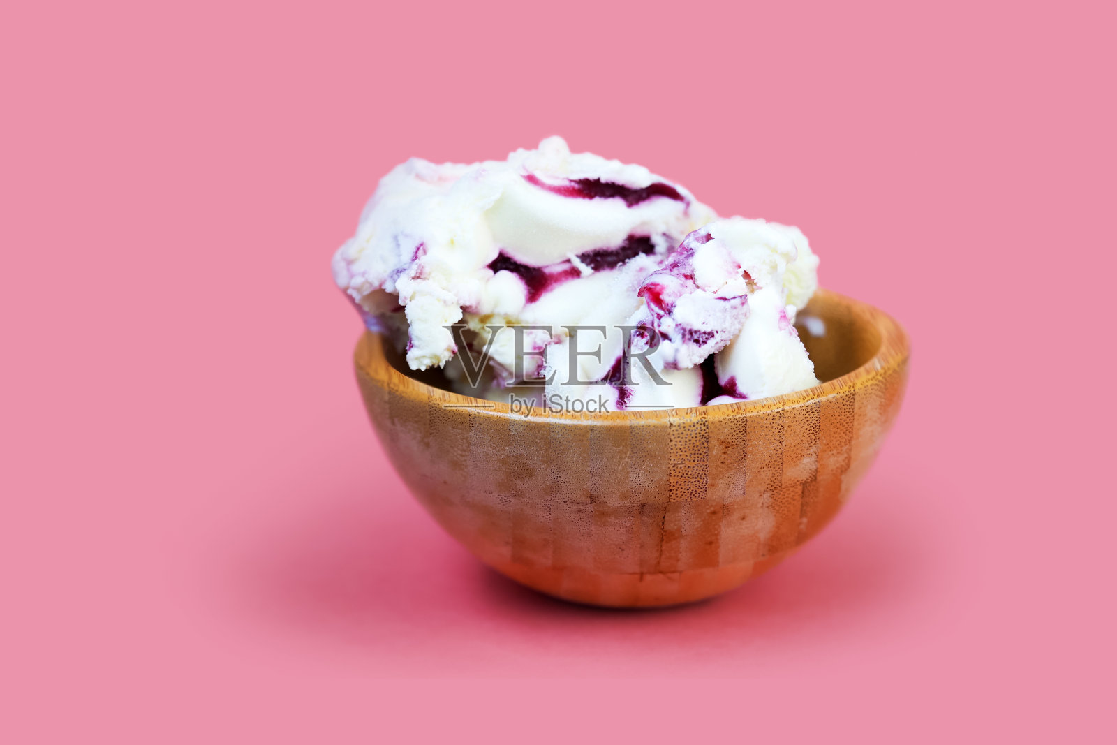 奶油冰淇淋加浆果糖浆。冰淇淋在木碗孤立在粉红色的背景。食品背景概念照片摄影图片