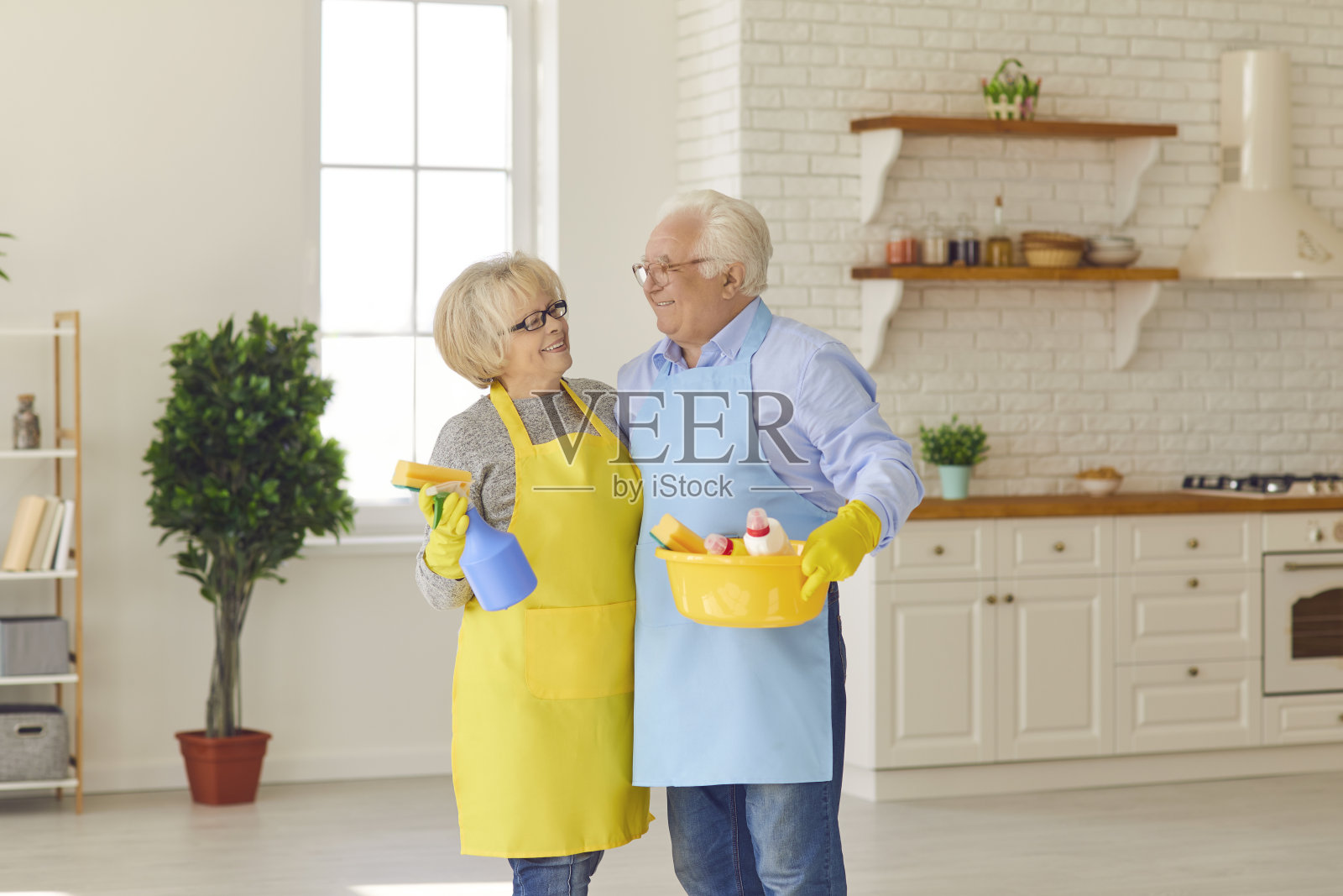 肖像迷人的资深夫妇在彩色保护手套和围裙看着对方。照片摄影图片