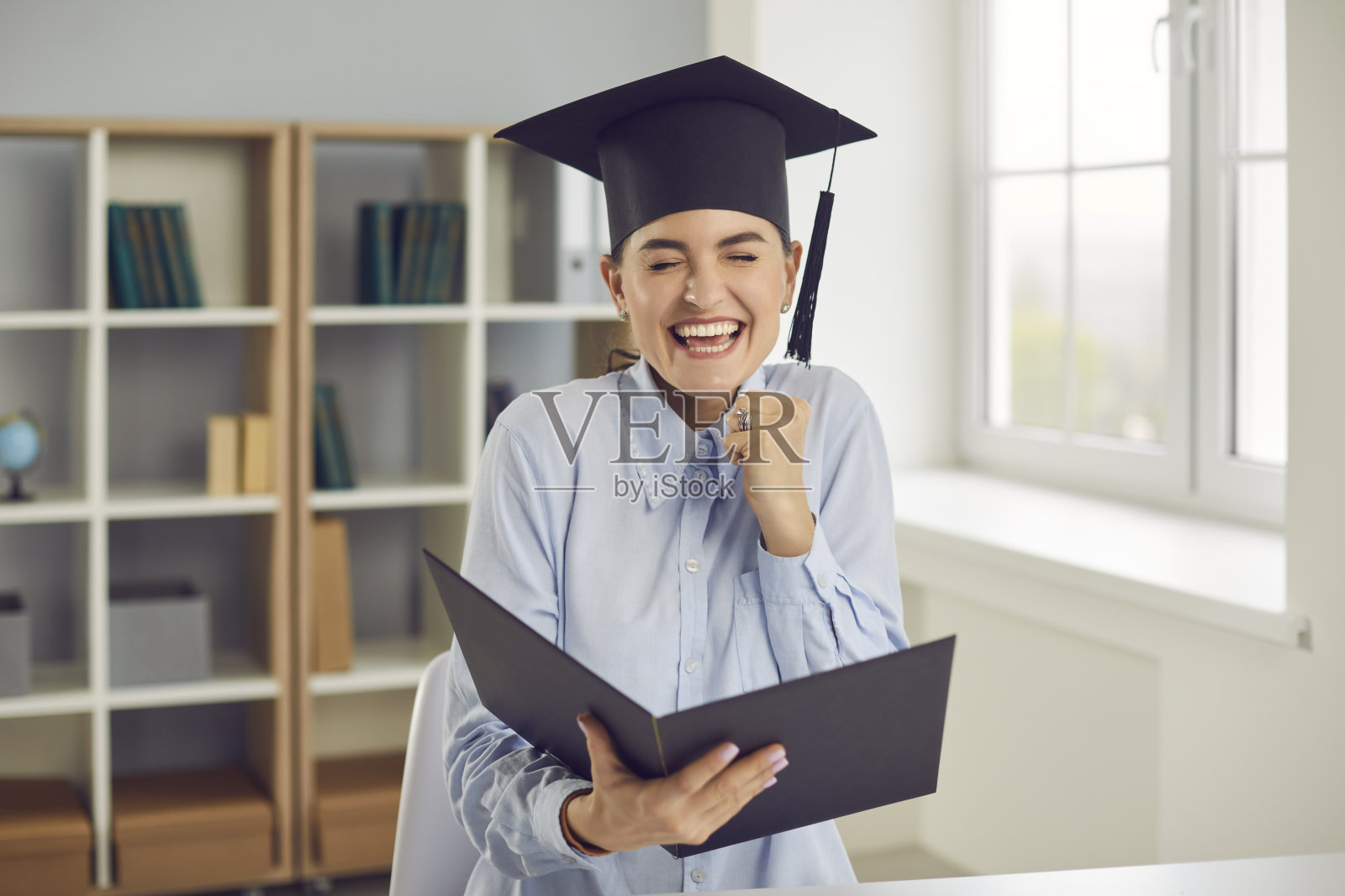 快乐的女毕业生是真诚地为她在文凭上看到的成绩感到高兴。照片摄影图片