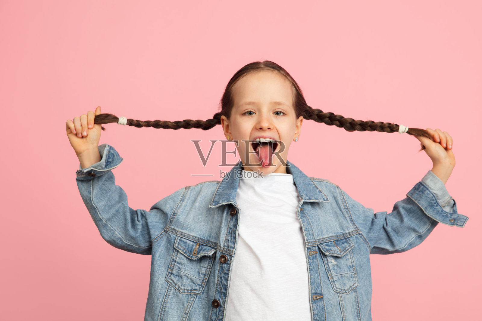 快乐的孩子，女孩被隔离在粉红色的工作室背景下。看起来开心，开朗，真诚。Copyspace。童年，教育，情感概念照片摄影图片