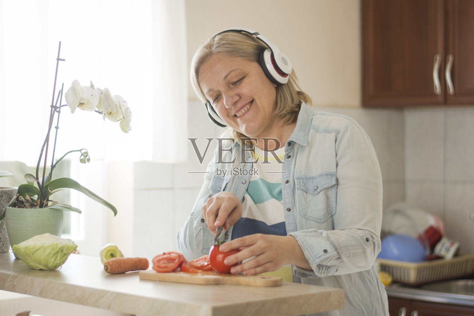 一个快乐的老妇人正在准备素食晚餐照片摄影图片