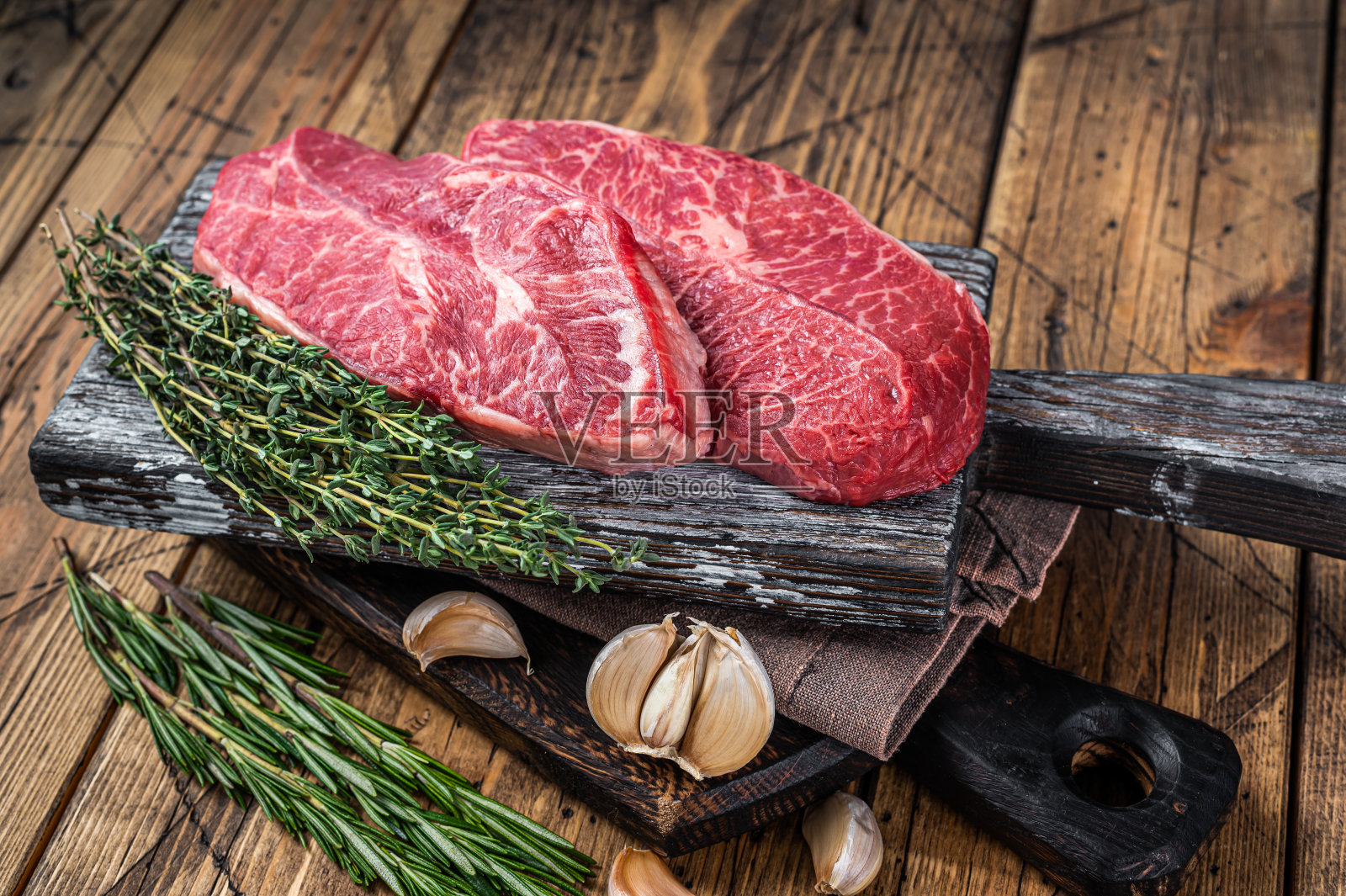 生肩上刀锋牛肉牛排在一个木制的屠夫板与香草。木制背景。俯视图照片摄影图片