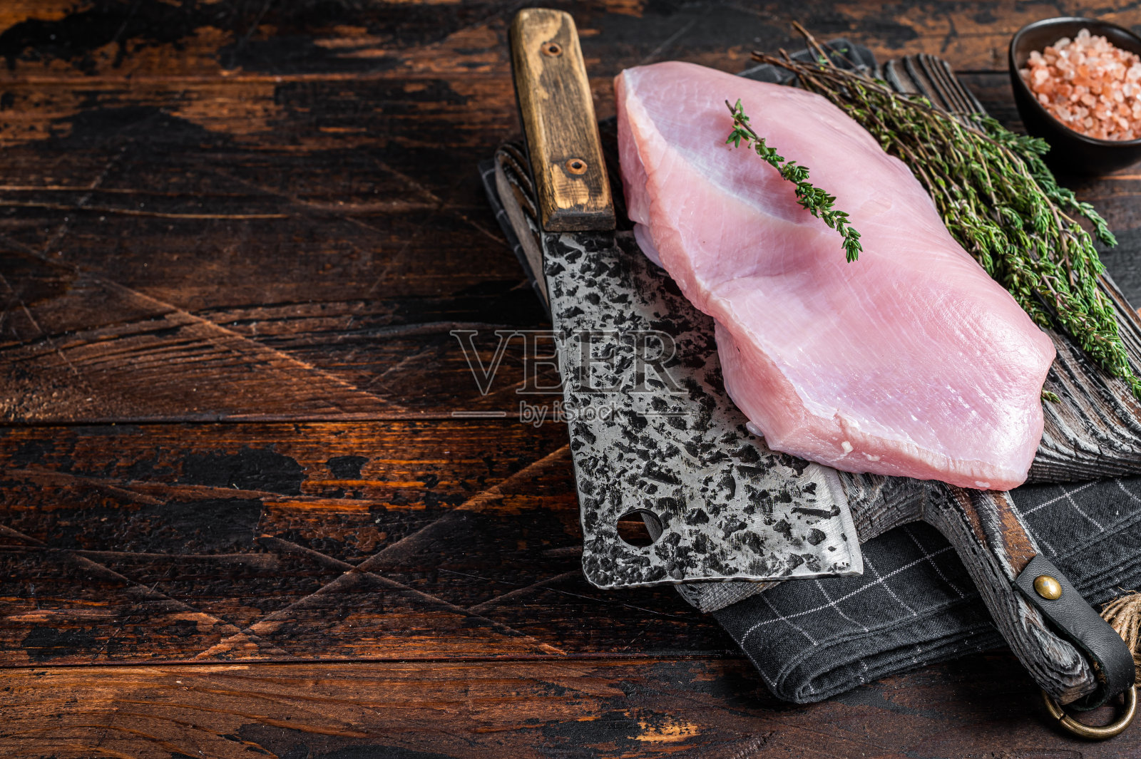 用切肉刀将生火鸡胸肉放在木板上。深色木制背景。前视图。本空间照片摄影图片