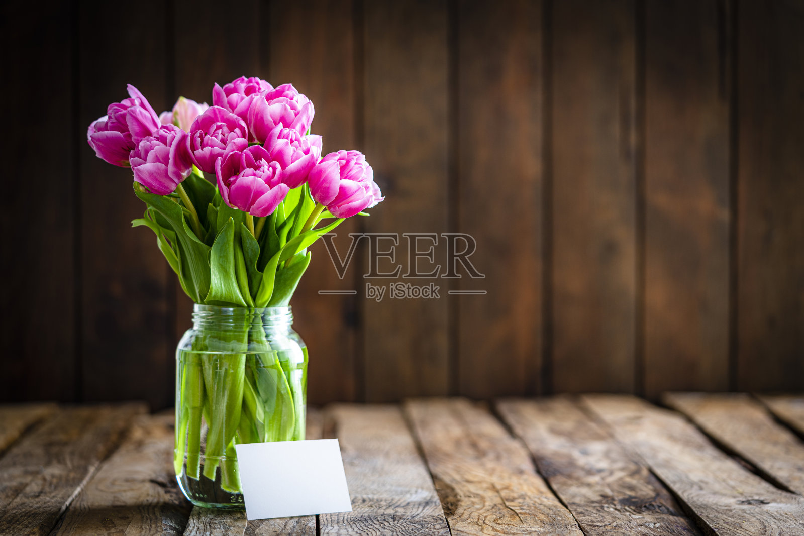 玻璃瓶里有粉色郁金香花束和空白卡片照片摄影图片