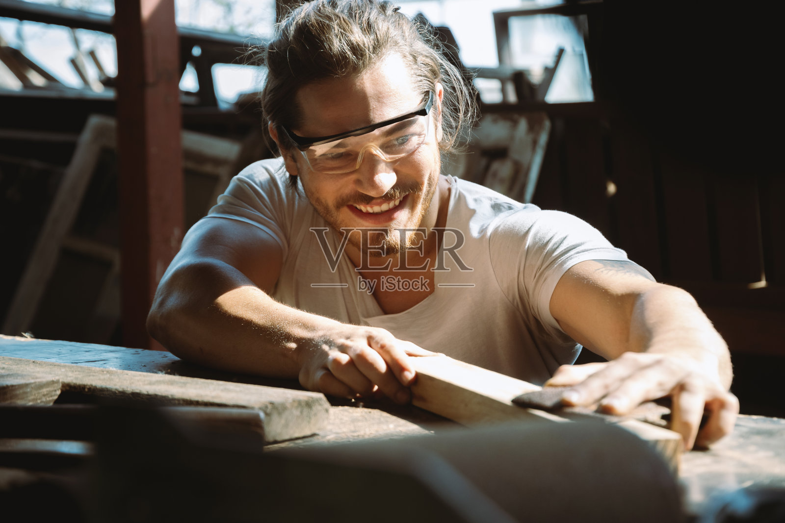 男木匠的肖像在木材车间用砂纸给木材打磨。照片摄影图片
