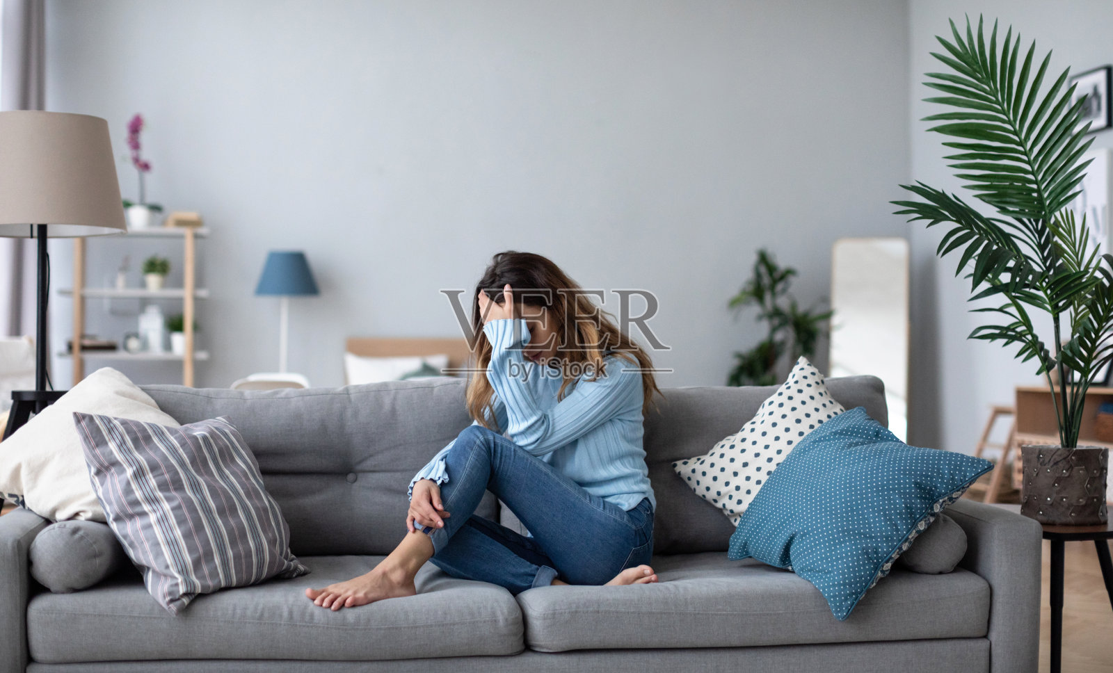 年轻女子坐在沙发上，心事重重，心理有问题。照片摄影图片