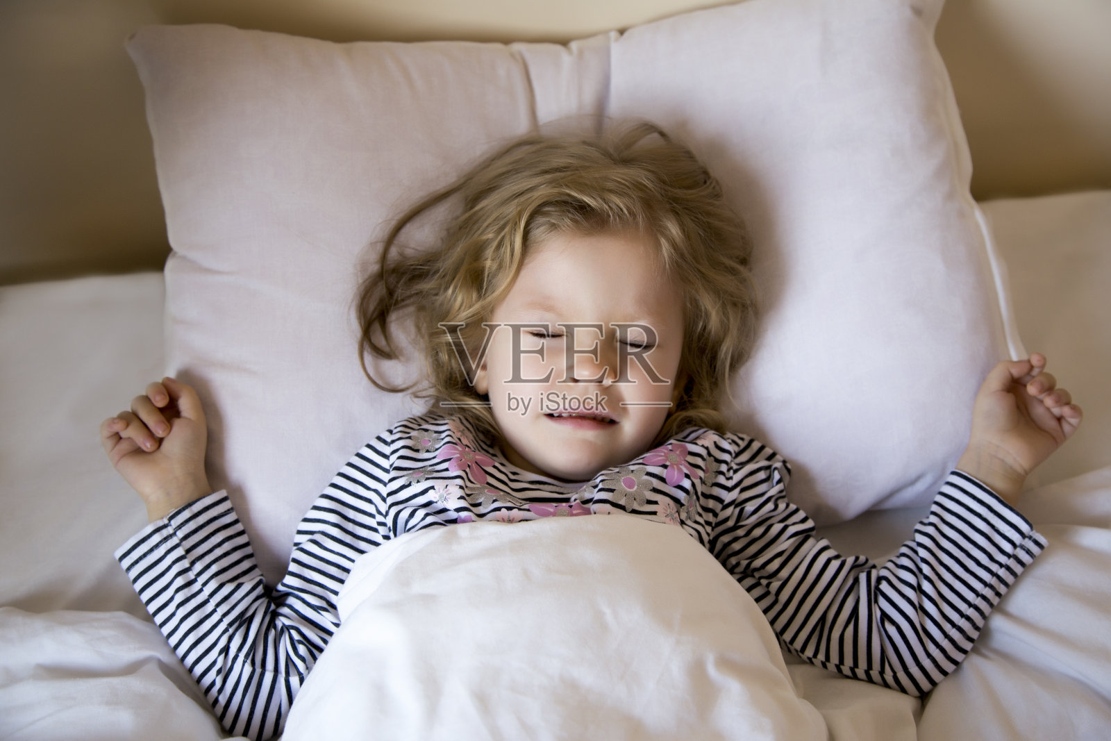 在明亮的背景下，小女孩甜美地睡在白色的枕头上。健康的概念。照片摄影图片