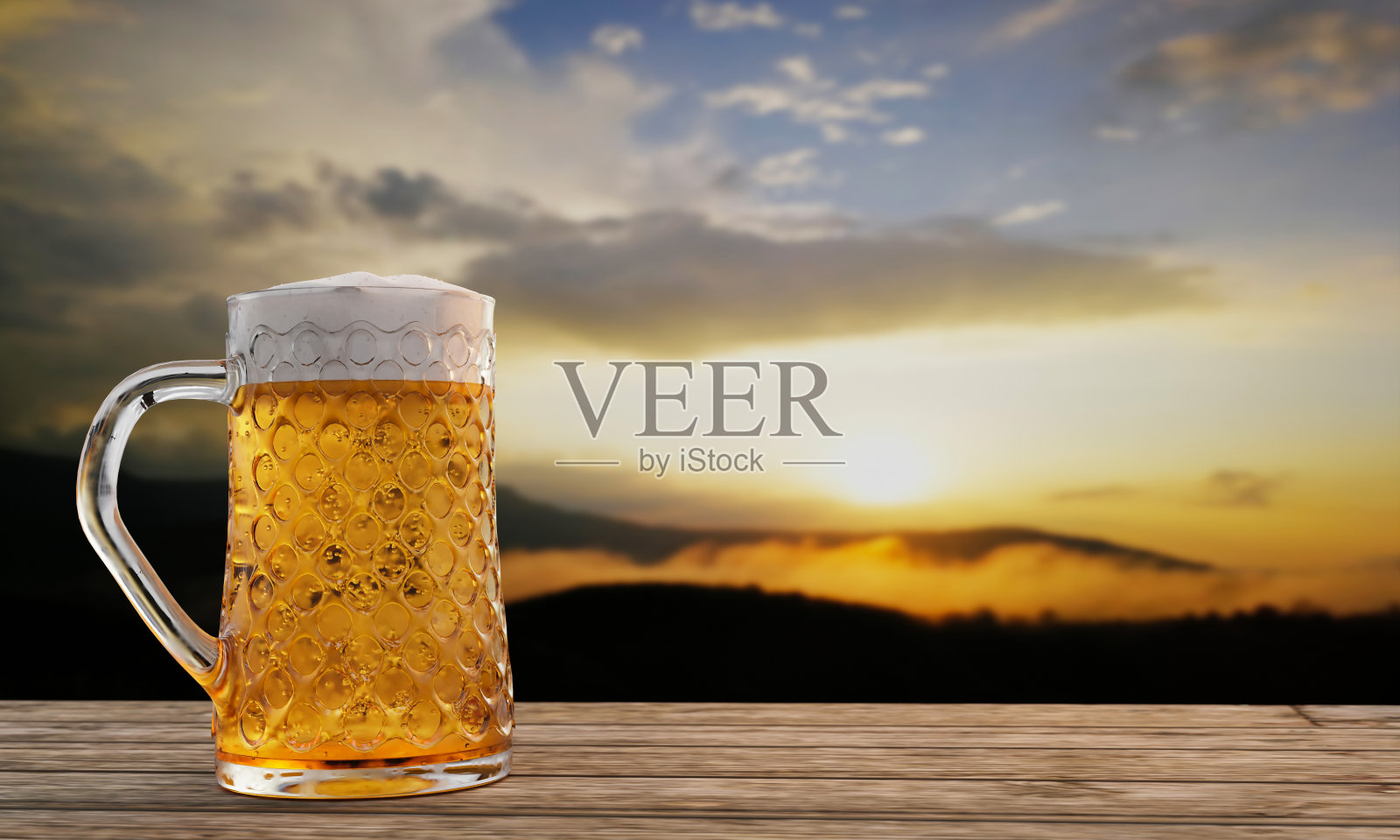 清澈的啤酒杯，杯口有冰啤酒和泡沫，杯口有水滴附着。木板或木板表面，并与山风景在早晨的阳光。三维渲染照片摄影图片