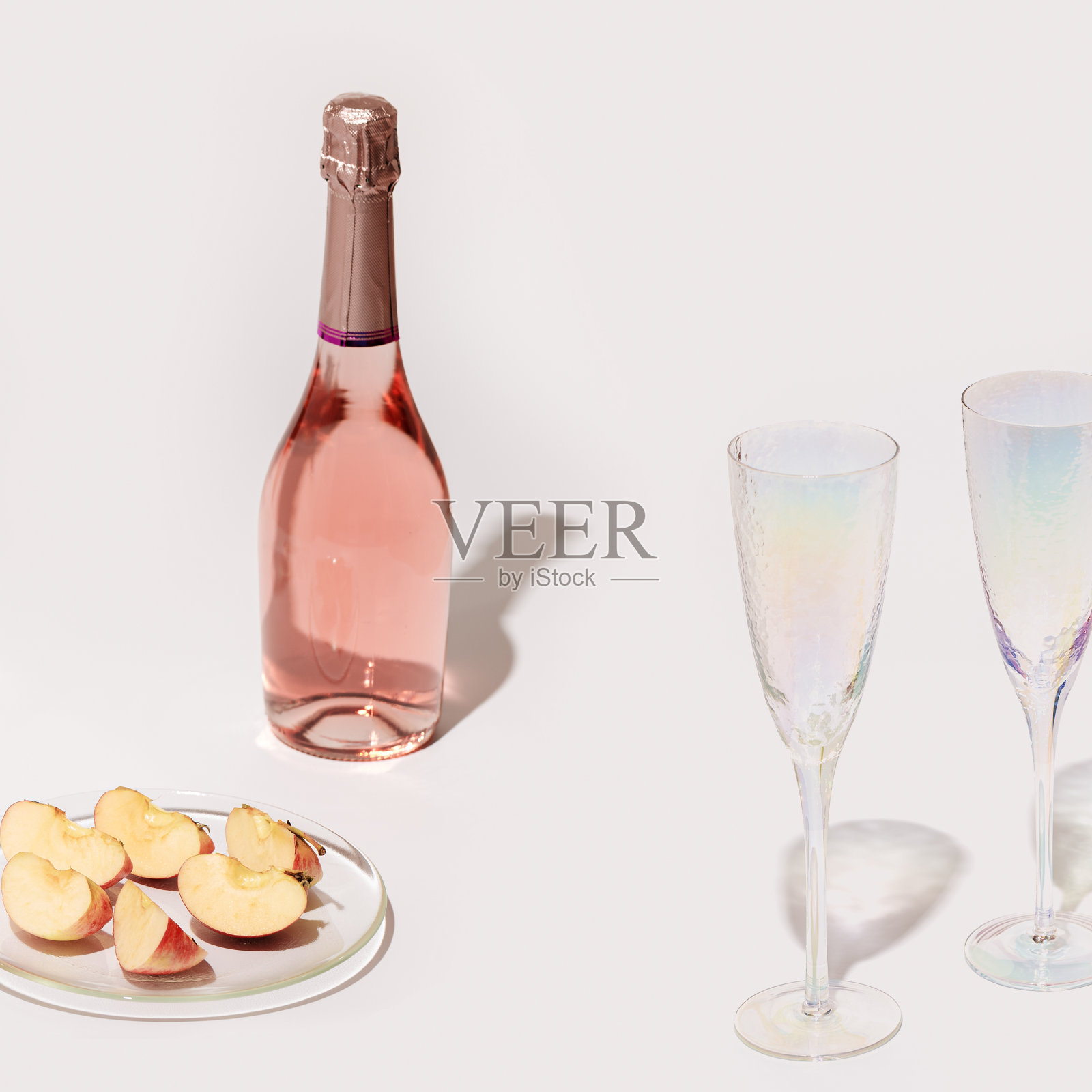 Ð:一瓶玫瑰葡萄酒，两只水晶玻璃杯，透明的盘子上放着苹果水果照片摄影图片