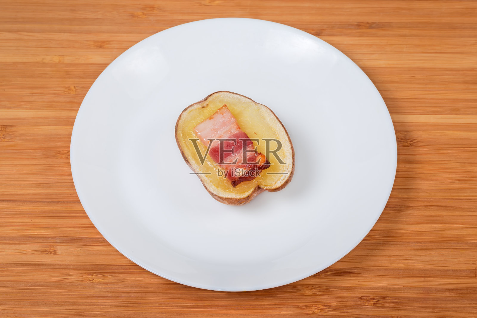 白盘上半烤土豆配培根片照片摄影图片