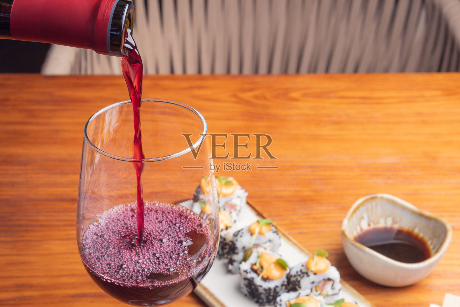 用玻璃杯盛红酒，木桌上放寿司卷。寿司和红酒菜单。日本食品照片摄影图片