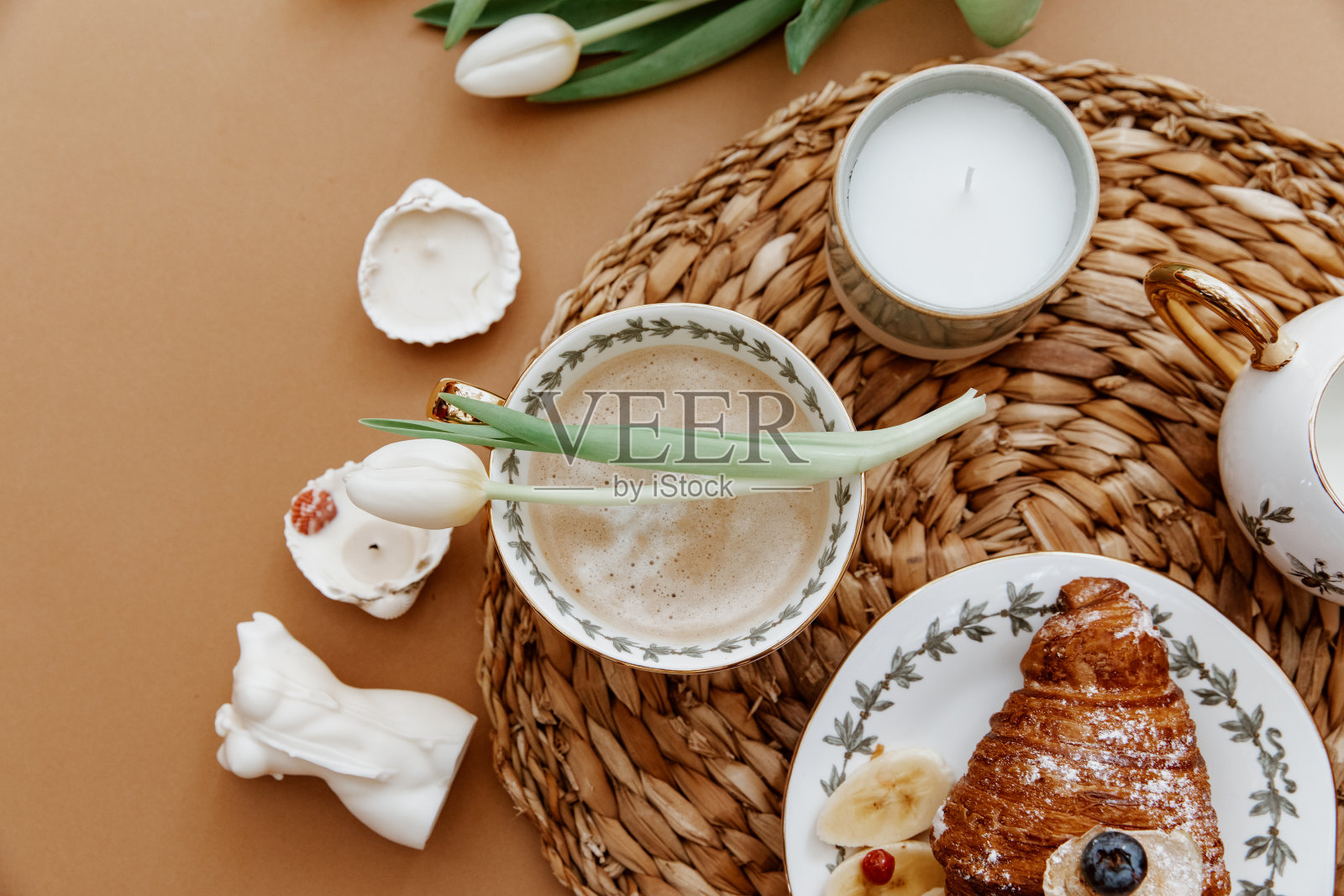 3月8日母亲节的早晨咖啡。咖啡杯，棕色背景的羊角面包。新鲜的白色郁金香。春天概念，静物构图照片摄影图片