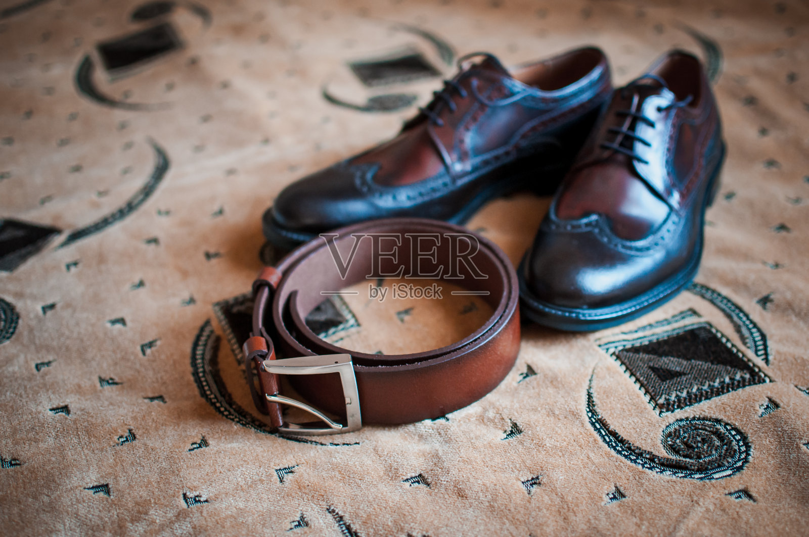 男人的鞋子和棕色皮带放在地毯上照片摄影图片