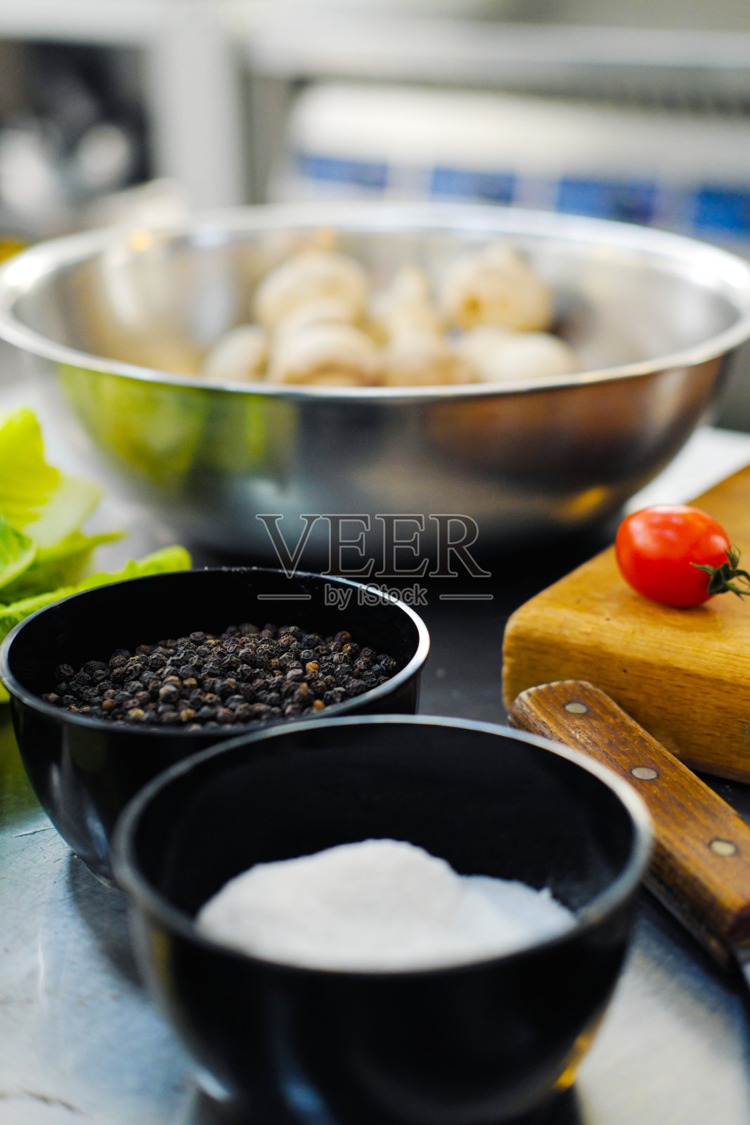 厨房桌子上的碗里放着胡椒、豌豆和盐。照片摄影图片