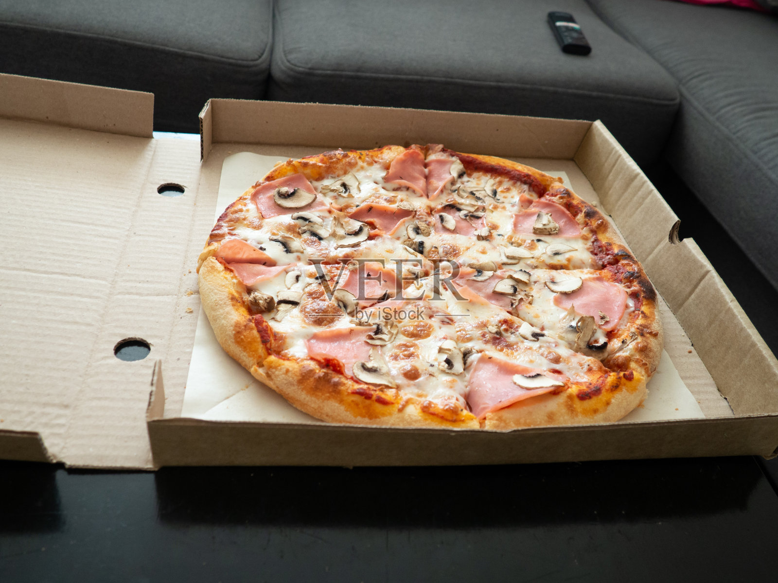 房间的桌子上有一个打开的盒子里的披萨照片摄影图片