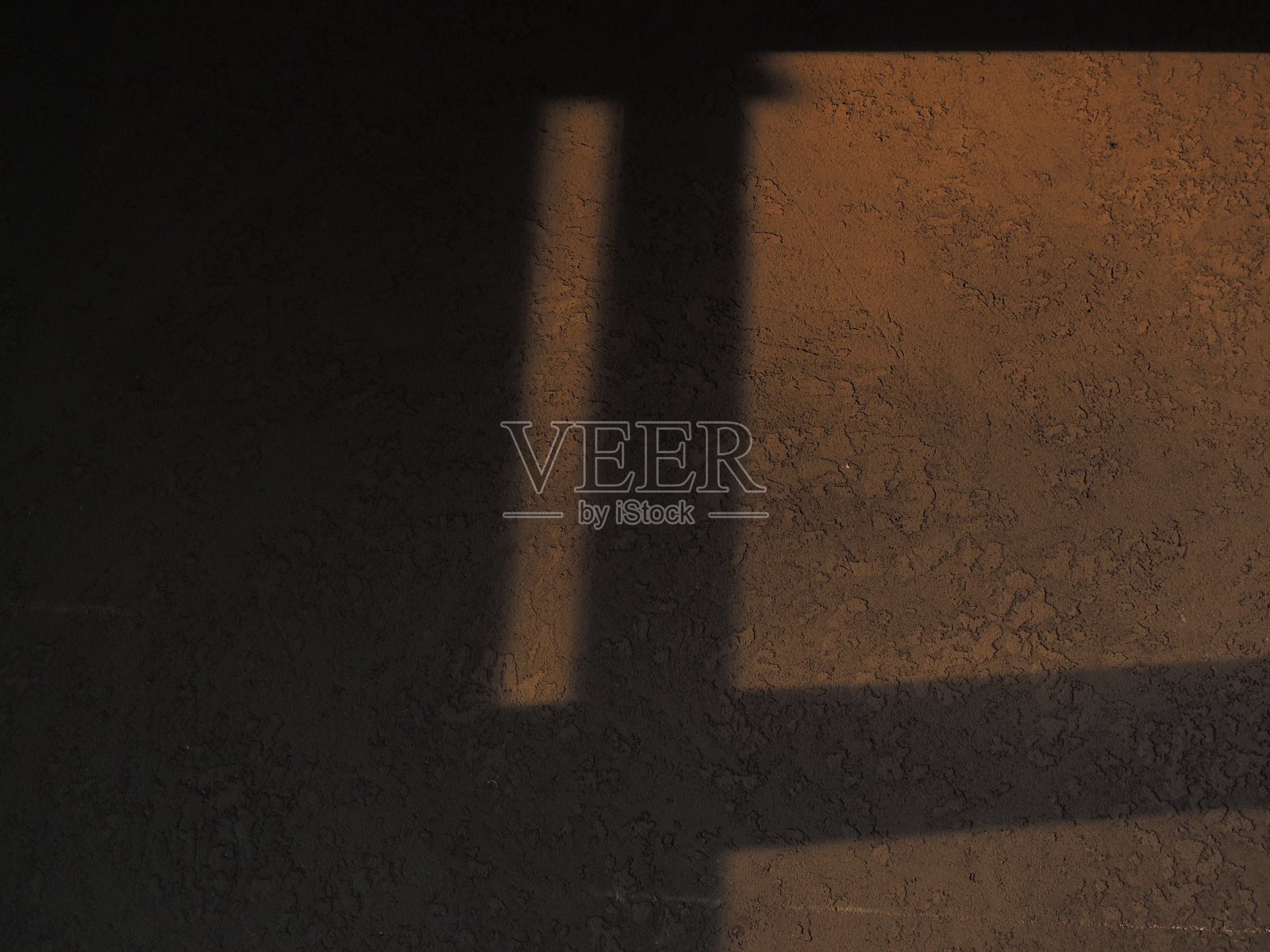 窗户的影子映在黑暗而有纹理的墙上。日落时明亮的光线。照片摄影图片