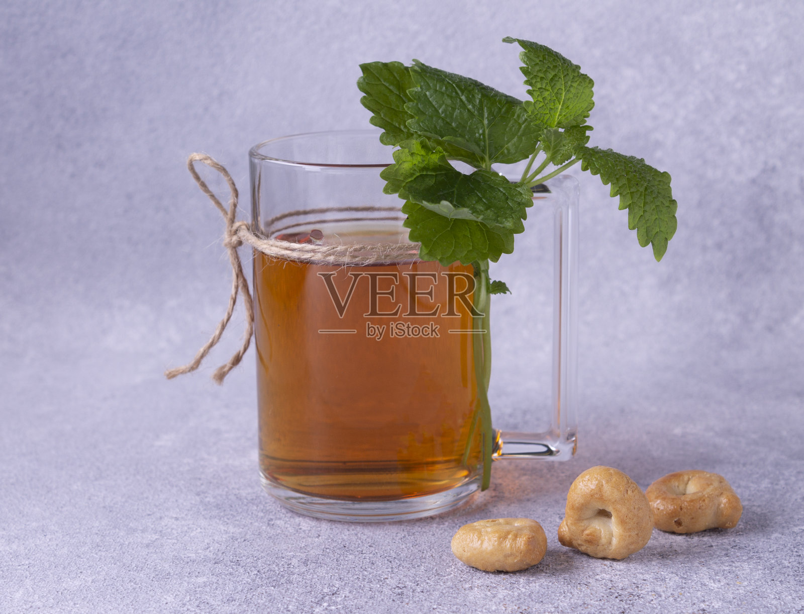 杯子里放着茶和薄荷枝，白底上放着饼干。照片摄影图片