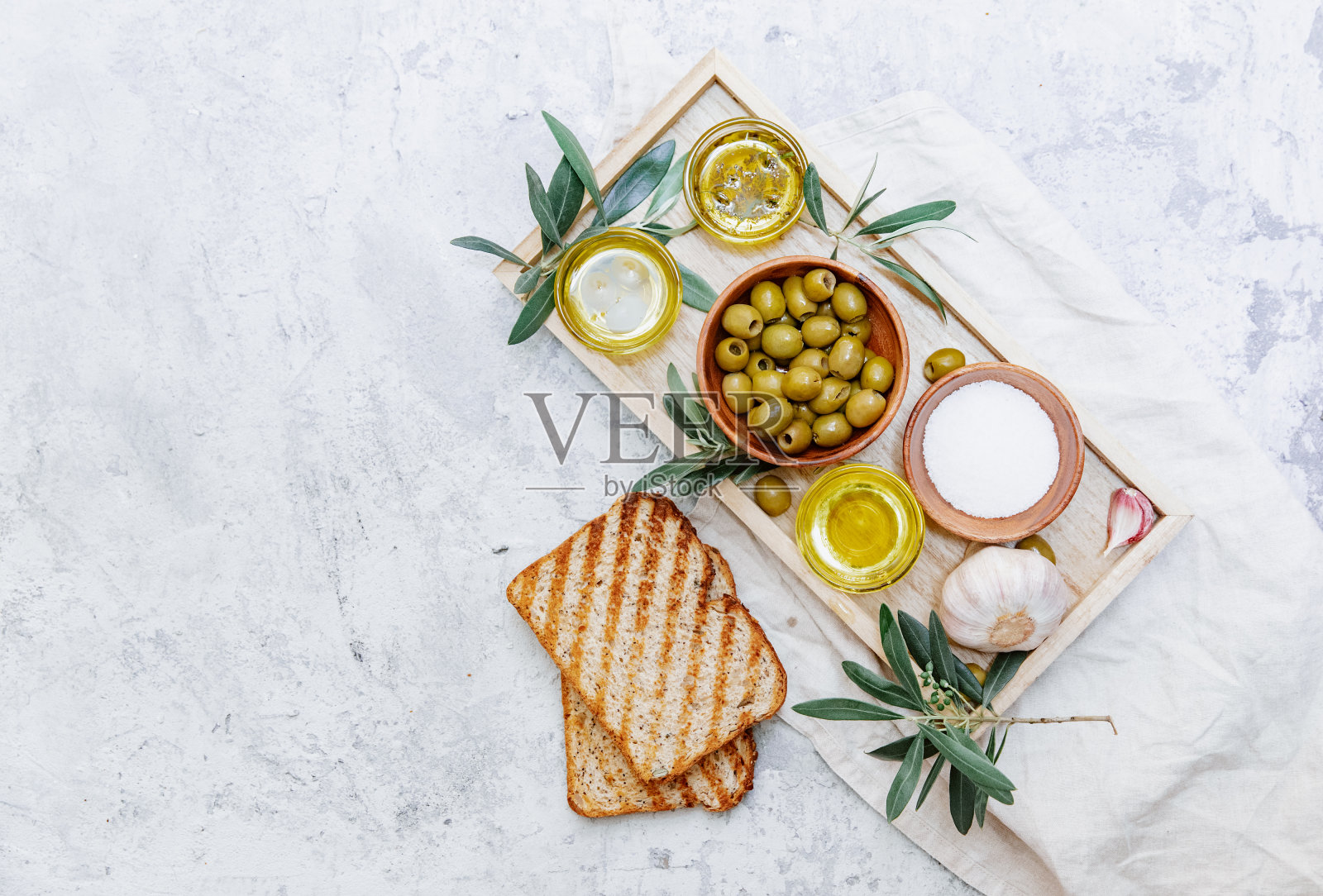 将橄榄油、橄榄和橄榄枝平铺在正上方的白色背景上。有机新鲜橄榄油。照片摄影图片