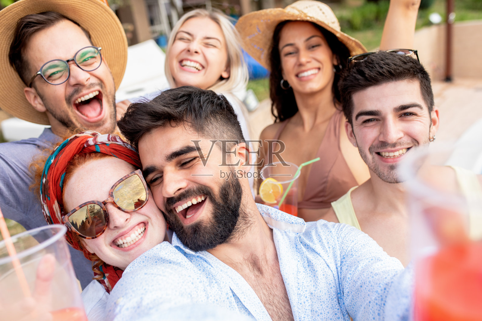 一群年轻人在暑假和享受一个泳池旁的派对。照片摄影图片