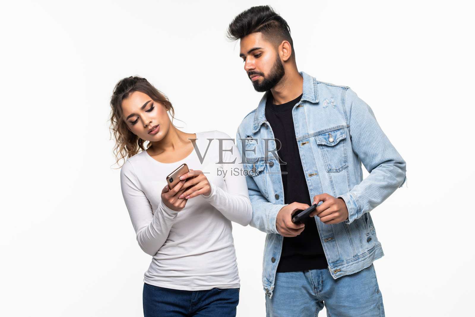 嫉妒的印度年轻女子偷看她的男朋友的手机孤立在白色的背景照片摄影图片