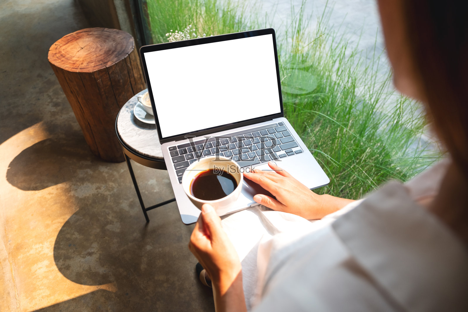 一位女士在咖啡馆喝咖啡的时候，正在使用并触摸笔记本电脑的触控板，白色的桌面屏幕照片摄影图片