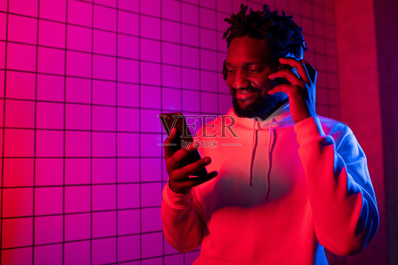 黑人戴着耳机听音乐，跳舞。红色蓝色背景照片摄影图片