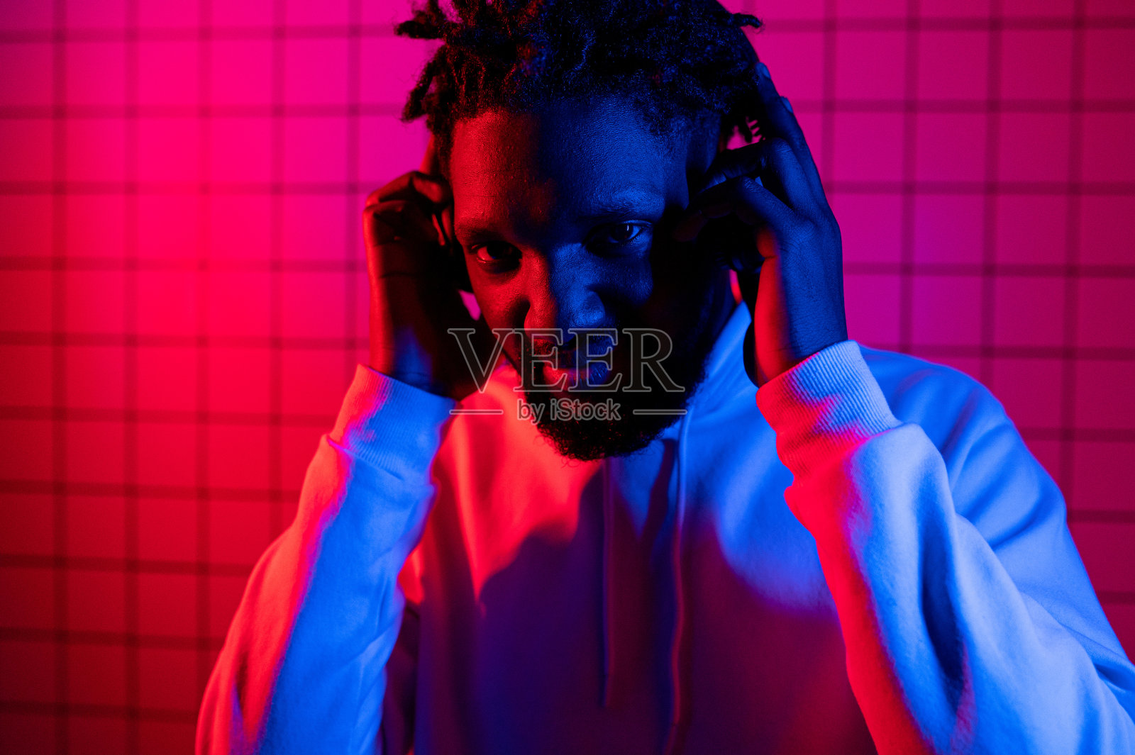 音乐的概念。一个黑人戴着耳机听着音乐，背景是霓虹灯。红色和蓝色背景照片摄影图片