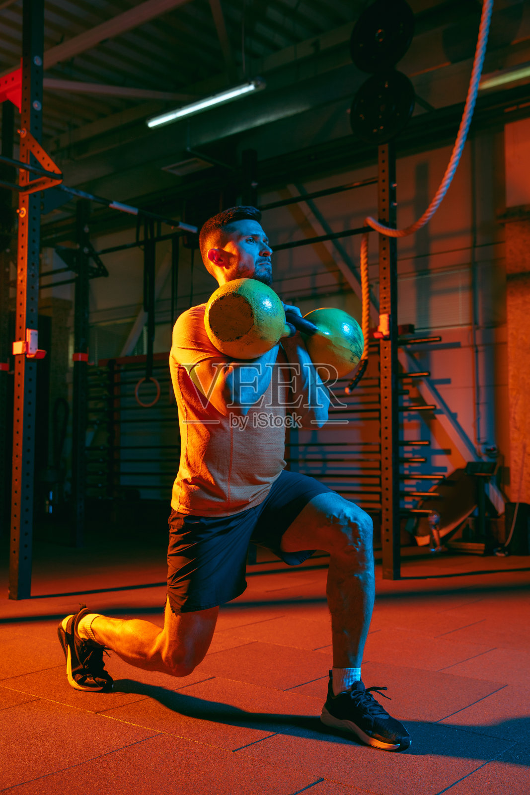 年轻的运动员，健身教练在混合霓虹灯光下训练。照片摄影图片