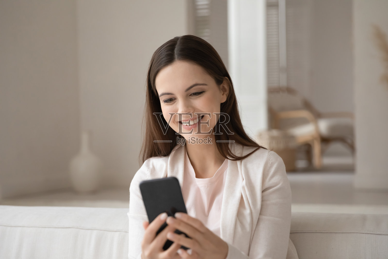 积极的年轻女士坐在沙发上享受智能手机聊天照片摄影图片