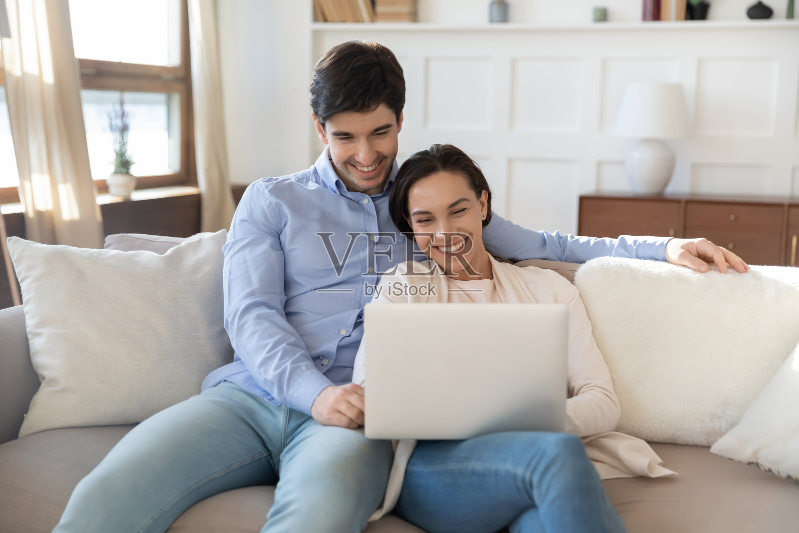 快乐的年轻夫妇使用笔记本电脑，一起在沙发上放松照片摄影图片