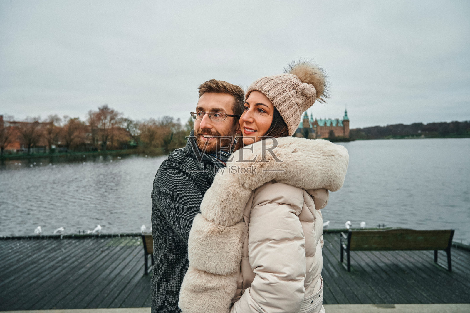 这是一对深情的年轻夫妇在城市的一天里站在湖边拥抱的镜头照片摄影图片