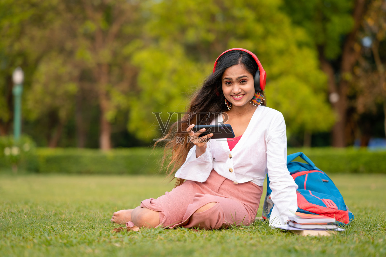 年轻女学生在校园公园用手机和耳机看视频照片摄影图片