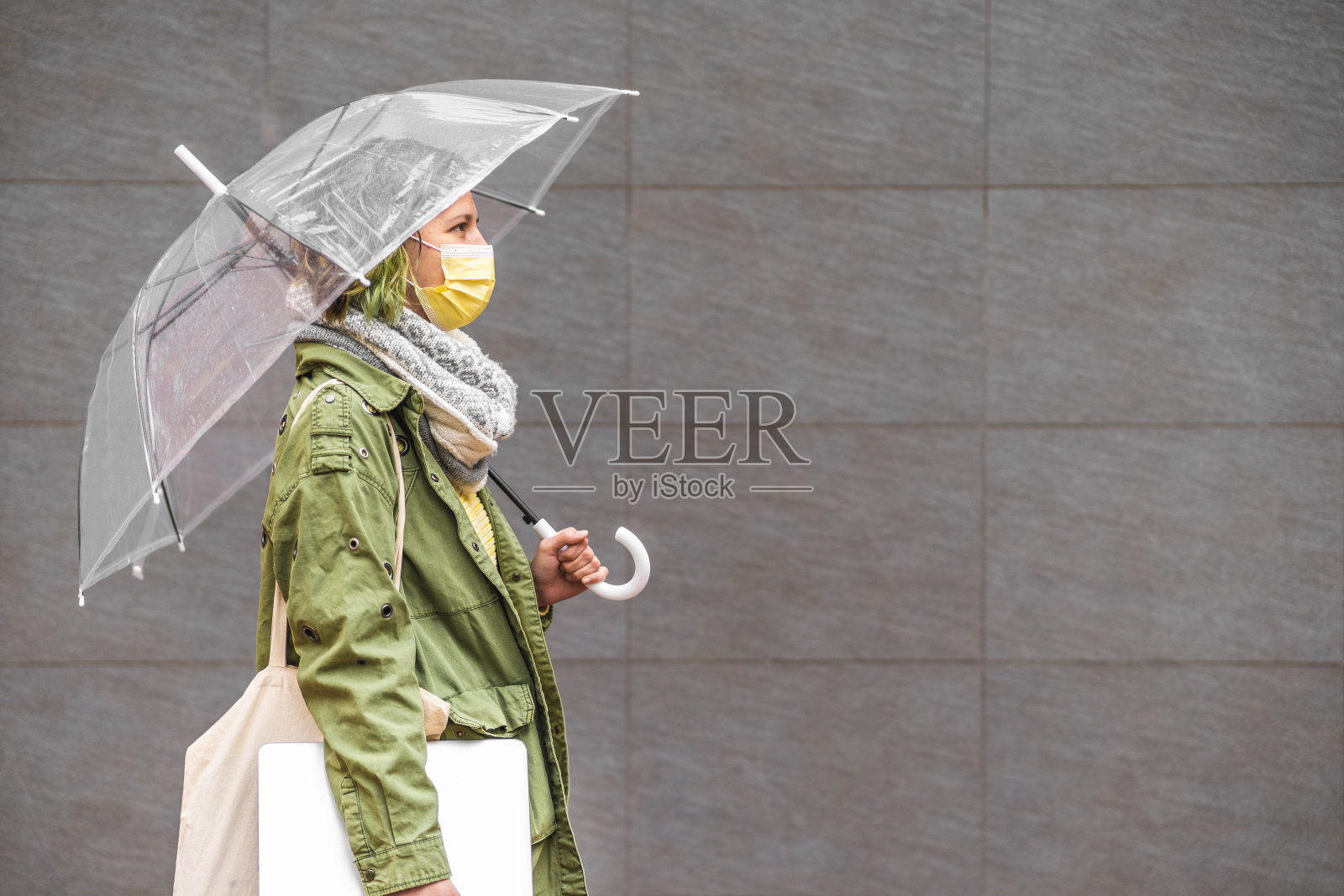 一名西班牙妇女带着雨伞和防护面具走在西班牙卡斯特隆市的街道上照片摄影图片