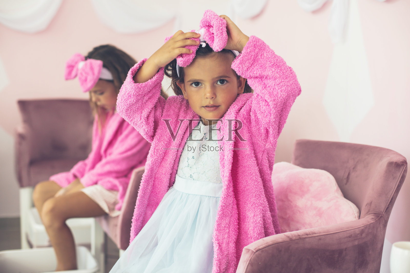 两个穿着浴袍的小女孩在水疗中心。照片摄影图片