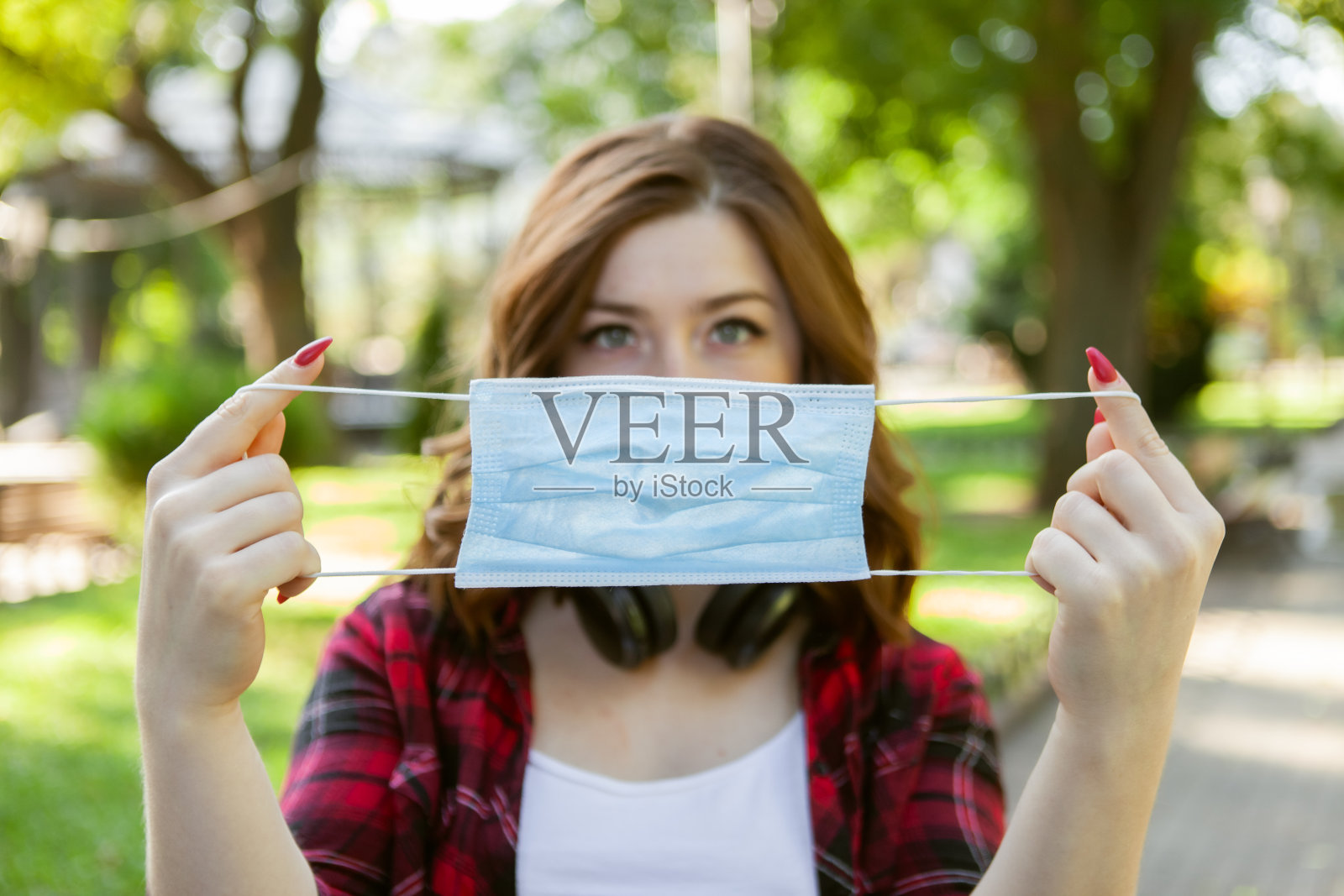 一名年轻女子在户外展示一个医用口罩。病毒防护照片摄影图片