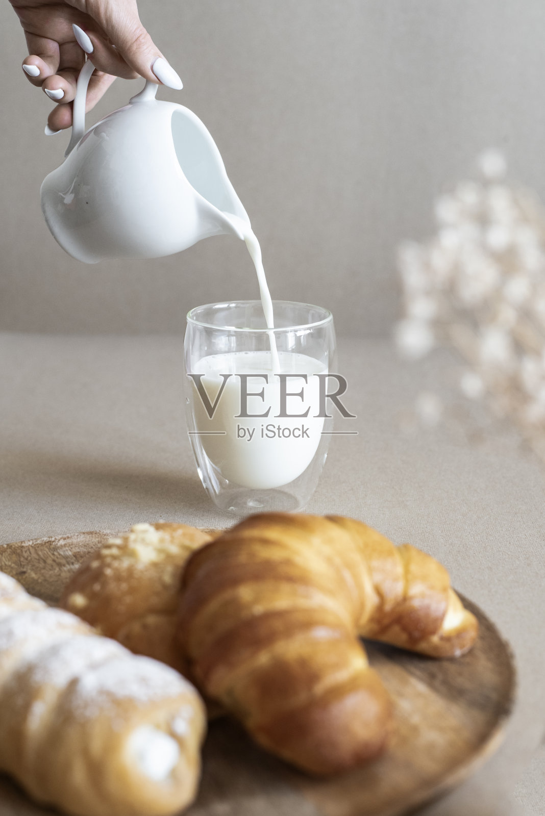 往玻璃杯里倒入牛奶和法式糕点照片摄影图片