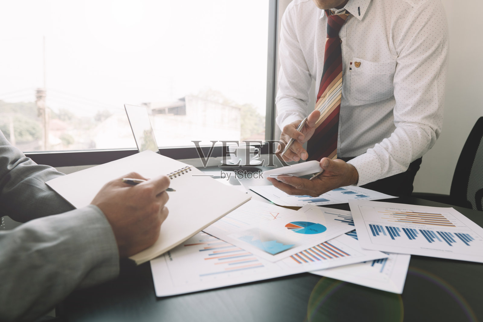 商人用计算器为同事计算公司的财务报表，查看并共同解决公司内部的问题。企业财务和会计概念照片摄影图片