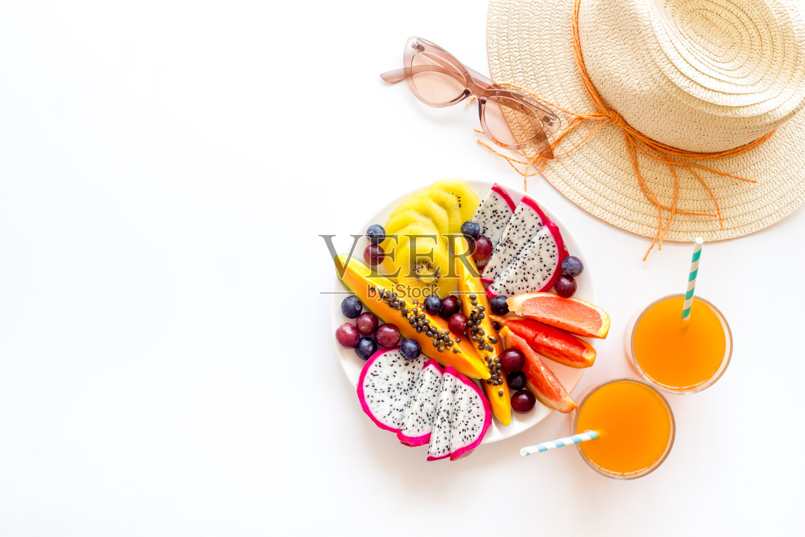 度假热带水果早餐。水果与新鲜的果汁和帽子，俯视图照片摄影图片