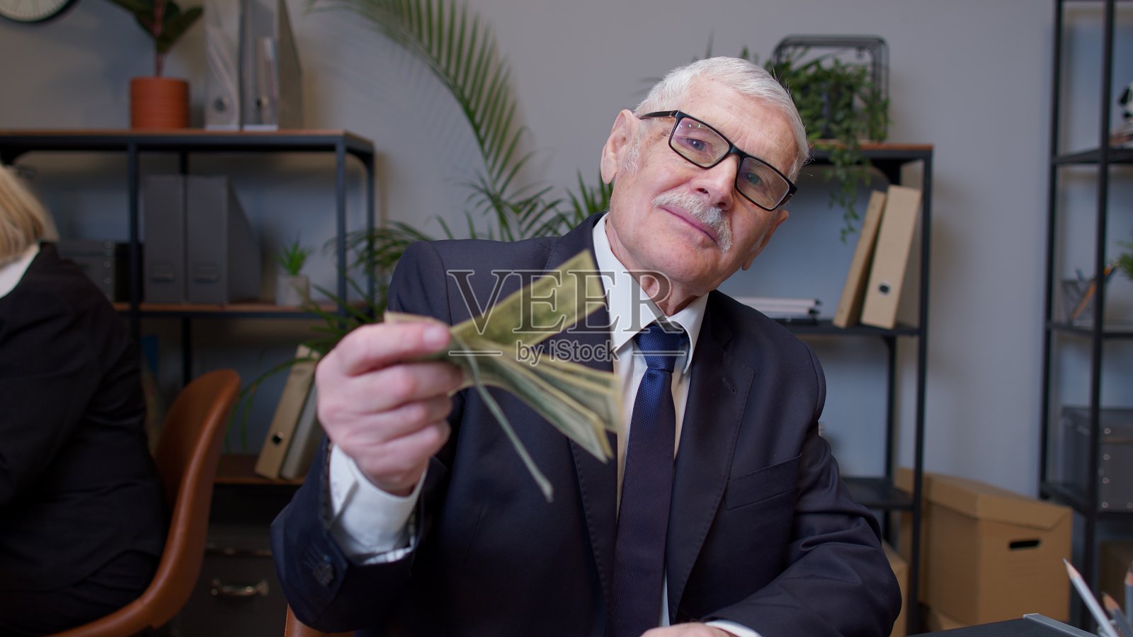 微笑的高级商务人士挥舞着一叠钱在办公室工作后的成功在线工作照片摄影图片