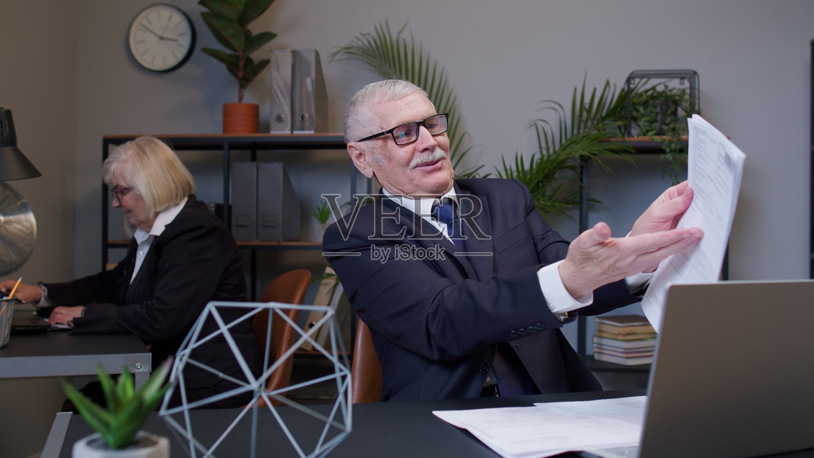 一位老人在办公室阅读文件、财务文件时，为实现目标而感到幸运和高兴照片摄影图片