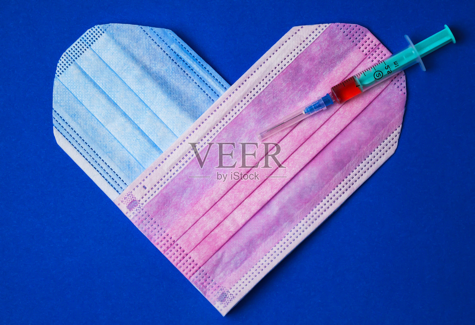 医用注射器，从医用口罩上给心脏注射一剂药。照片摄影图片