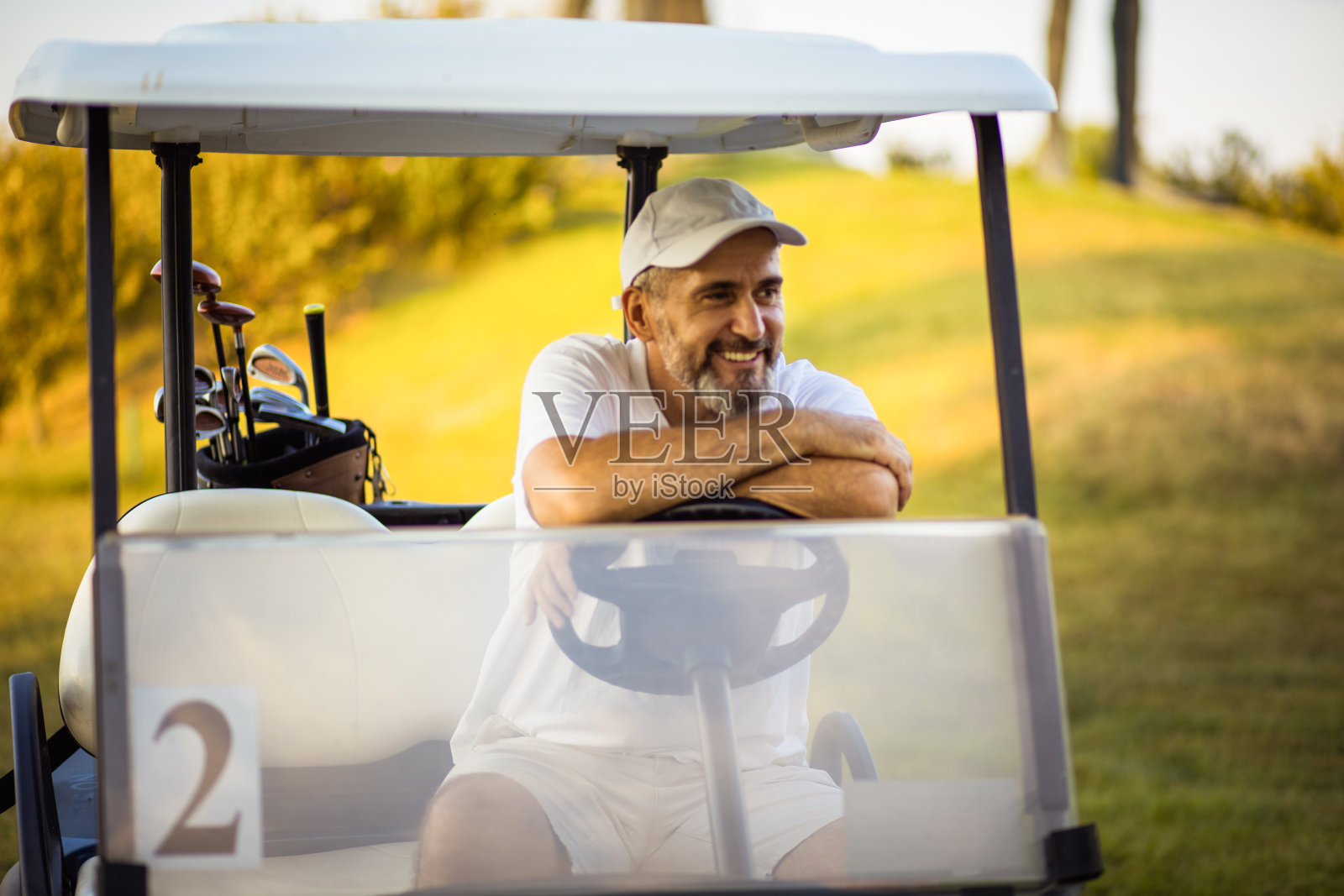 坐在高尔夫车里的老人。照片摄影图片