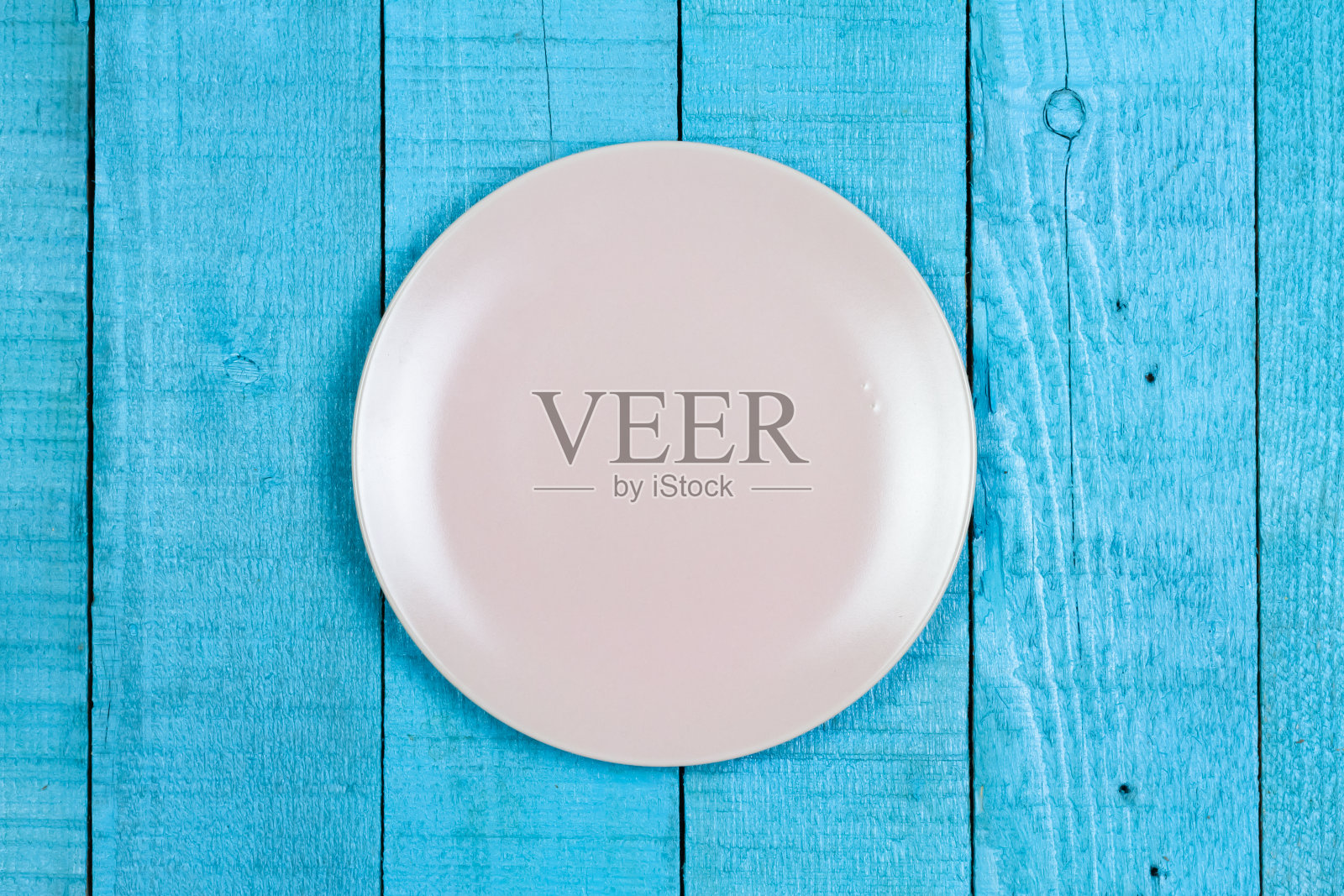 空的粉红色陶瓷板上的蓝色木制背景。照片摄影图片