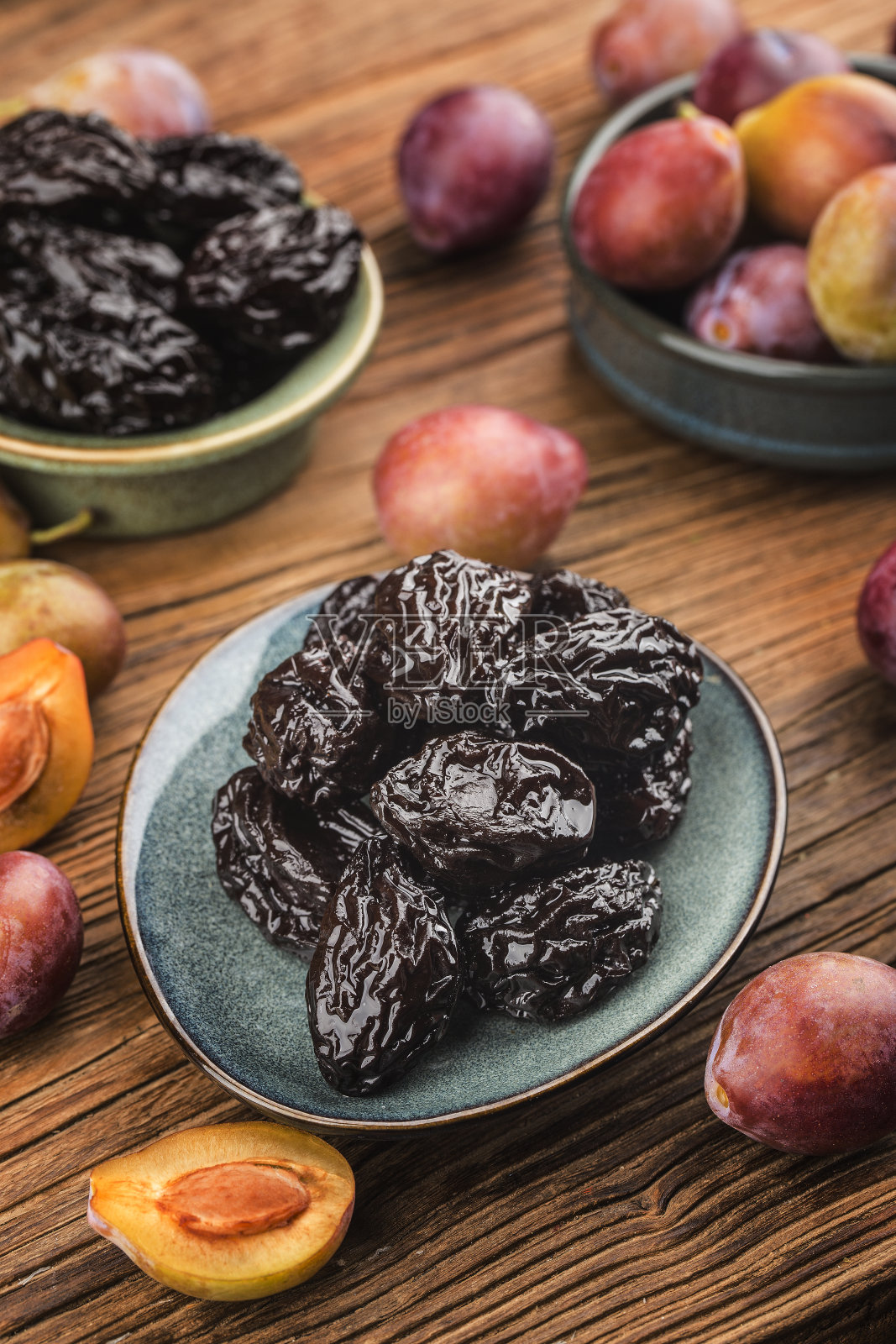 在木板背景上加上新鲜的梅干和干梅干照片摄影图片